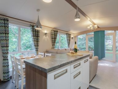 A living room with a sofa and dining area at Fern View -Kelling Heath Holiday Park, Weybourne near Sheringham