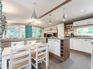 A kitchen and dining area with table and chairs at Fern View -Kelling Heath Holiday Park Weybourne near Sheringham