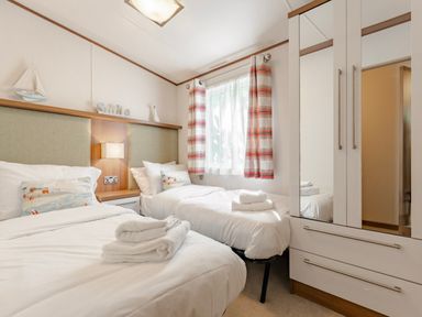 A bedroom with two beds and a wardrobe at Fern View -Kelling Heath Holiday Park Weybourne near Sheringham