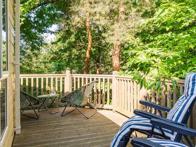 A deck area with chairs and a table at Fern View -Kelling Heath Holiday Park in Weybourne near Sheringham
