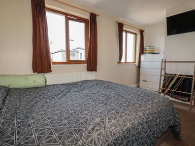 A bedroom with a bed and windows at Carnweather in Newquay