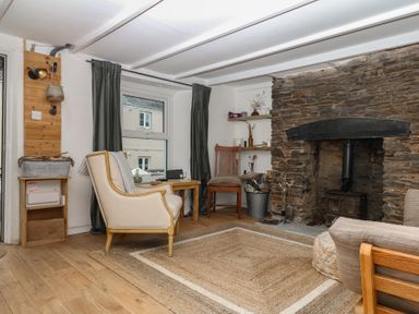 A living room featuring a stone fireplace and wooden furniture at Bedford Cottage in Yelverton