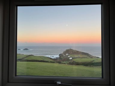 A view of ocean and hill with a lighthouse at Cape View in Cape Cornwall near St Just