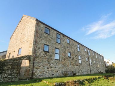 A stone building with windows and benches at Cape View near St Just