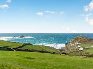 A view of the ocean and cliff with houses and a lighthouse at Cape View near Cape Cornwall