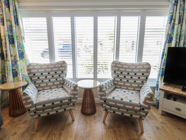 Two patterned chairs and a table with a view through the window at 7 Longstone Close Chathill
