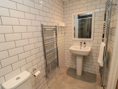 A bathroom with a sink, toilet, and shower at 7 Longstone Close in Chathill