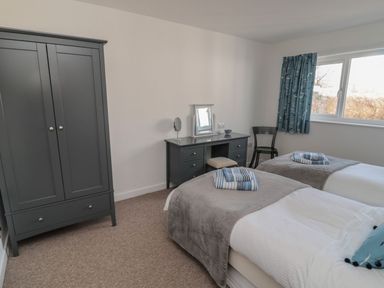 A bedroom with two beds and a desk at 7 Longstone Close in Chathill