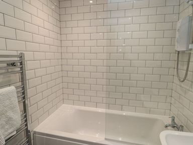 A bathroom with a bathtub and shower at 7 Longstone Close in Chathill