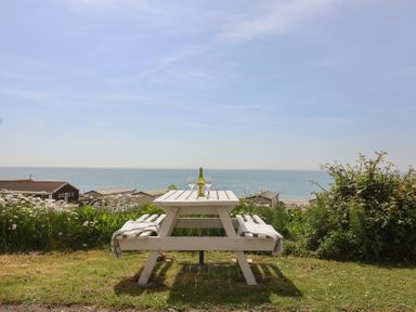 A table with a bottle and glasses overlooking the sea at Salt & Stone Lyme Regis
