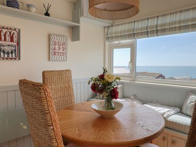 A dining room with a table and flowers at Salt & Stone in Lyme Regis