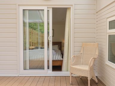 A balcony with a sliding door and a wicker chair at Salt & Stone Lyme Regis