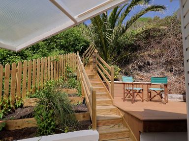 A wooden deck area with chairs and stairs at Salt & Stone Lyme Regis