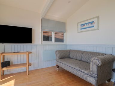 A living room with a sofa and television at Salt & Stone Lyme Regis