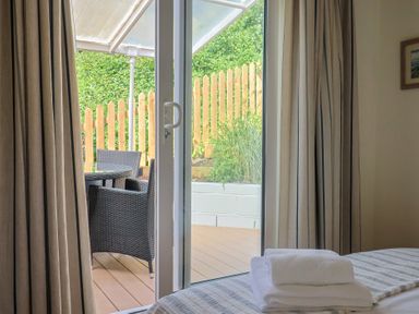 A bedroom with a door leading to an outdoor seating area at Salt & Stone in Lyme Regis