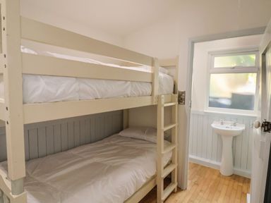 A bedroom with a bunk bed and a wash basin at Salt & Stone in Lyme Regis