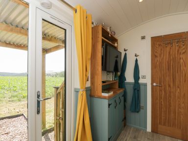 An entryway with a tv and a door at Daisy Shepherd's Hut in South Molton