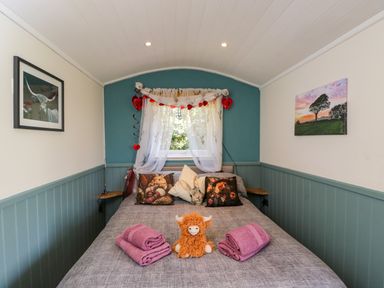A bedroom with a bed and decorative items at Daisy Shepherd's Hut in South Molton