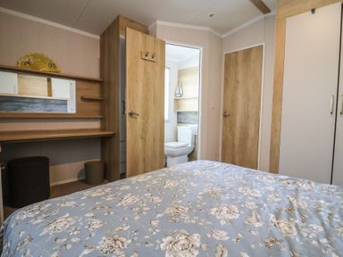 A bedroom with a desk and a bathroom door at Bordeaux Ladram Bay Otterton