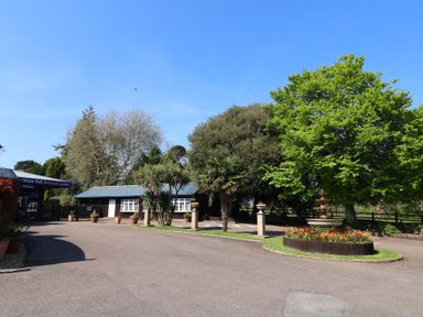 An entrance area with a sign and trees at Sicton Park Botanical Gardens in Ladram Bay Otterton