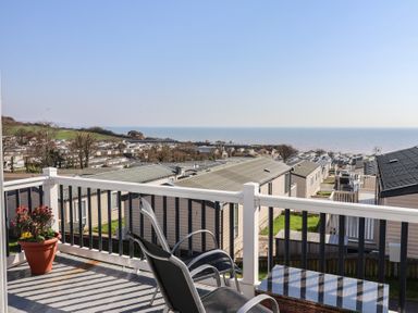 A balcony with a table and chair overlooking the sea at Bordeaux in Ladram Bay Otterton