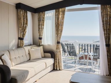 A living room with a sofa and a view of the sea at Bordeaux in Ladram Bay Otterton