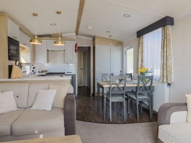 A living room with a dining area and kitchen cabinets at Bordeaux Ladram Bay Otterton