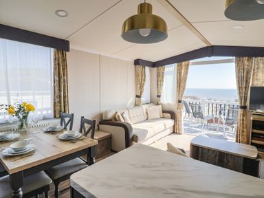 A living room with a sofa and dining table at Bordeaux in Ladram Bay Otterton