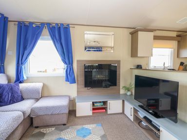 A living room with a sofa and televisions at PK Sunset View in Corton