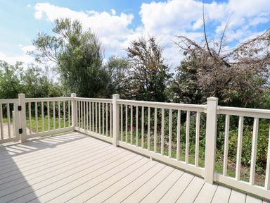 A deck area with railing and trees in the background at PK Sunset View in Corton