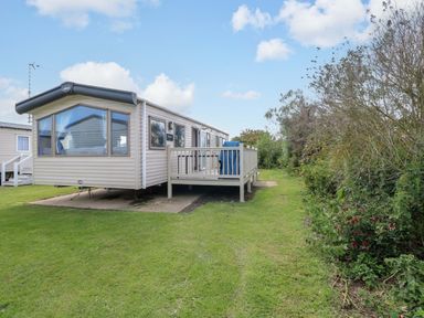 A mobile home with a decking area and lawn at PK Sunset View in Corton