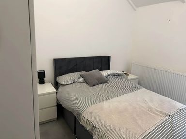A bedroom with a bed, bedside table, lamp and radiator at Llangollen - House - Sleeps 8- Garden, Llangollen