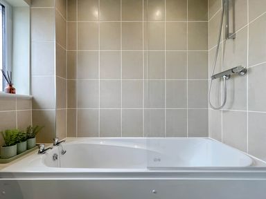 A bathroom with a bathtub and shower at 2 Bed House - Sleeps 4 - Garden - Parking - Wifi in Kendal