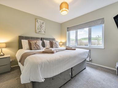A bedroom with a large bed and windows at 2 Bed House - Sleeps 4 - Garden - Parking - Wifi in Kendal