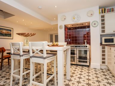 A kitchen with bar stools and kitchen appliances at Rhiwlas in Rhosneigr