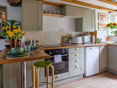 A kitchen equipped with oven, dishwasher, and table at Cotswolds Cozy Cottage Retreat - pet friendly, Finstock