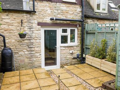 A garden with a stone wall and paving stones at Cotswolds Cozy Cottage Retreat - pet friendly, Finstock