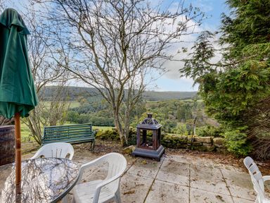 A garden with a table, umbrella, and chairs overlooking a valley view at Family Country Cottage with a private Valley View