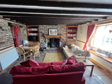 A living room with a sofa and dining table at Quiet cottage on the rural edge of Brixham