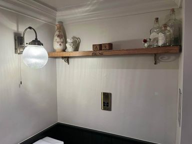 A shelf with decorative items and a light in a bathroom at Quiet cottage on the rural edge of Brixham