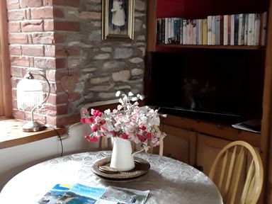 A dining room with a table, chairs, and a television at Quiet cottage on the rural edge of Brixham