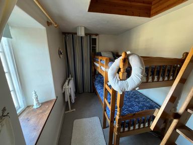 A bedroom with a bunk bed and window at Quiet cottage on the rural edge of Brixham