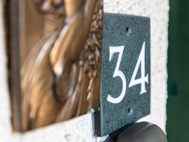 A door number 34 plaque on a wall outside a residential property in Bowness-On-Windermere