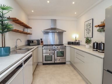 A kitchen with stove, sink, and microwave at Sea View, East Parade in Llandudno
