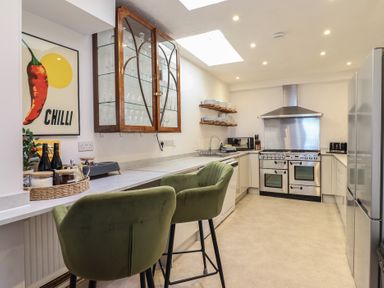 A kitchen with bar stools and appliances at Sea View, East Parade in Llandudno