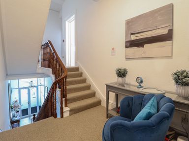A hallway with a staircase and a chair at Sea View, East Parade, Llandudno