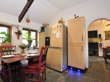 A kitchen with a dining table and refrigerator at Coach House, Camelford