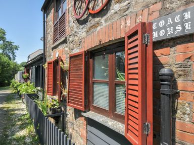 An outdoor view of the Coach House with windows and flowers at Coach House in Camelford