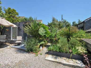 A garden with plant beds and outdoor seating at Coach House in Camelford