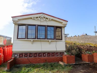 A mobile home with windows and bricks at Caravan at Argraig Llanrhyddlad near Cemaes Bay